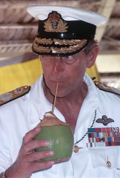 Prince Philip, Duke of Edinburgh, drinks from a coconut while watching traditional dancing on October 23, 1982 in Tarawa, Kiribati. Queen Elizabeth...