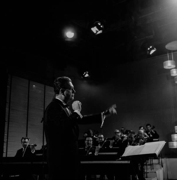 Composer Nelson Riddle conducting an orchestra, June 1962.