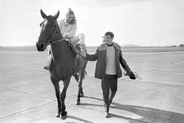 French actor Jean Paul Belmondo walking beside a horse mounted by Swiss actress Ursula Andress on the set of the film The Blue Max. 1966