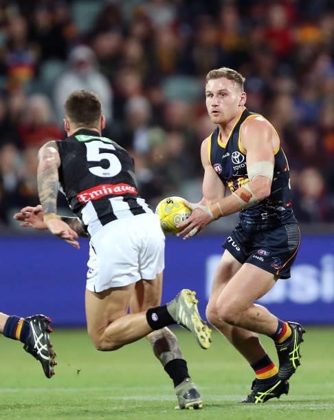 Rory Laird of the Crows runs the ball against Jamie Elliott of the Magpies during the 2021 AFL Round 12 match between the Adelaide Crows and the...