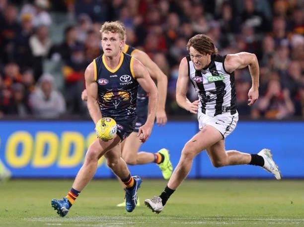Andrew McPherson of the Crows runs the ball against Nathan Murphy of the Magpies during the 2021 AFL Round 12 match between the Adelaide Crows and...
