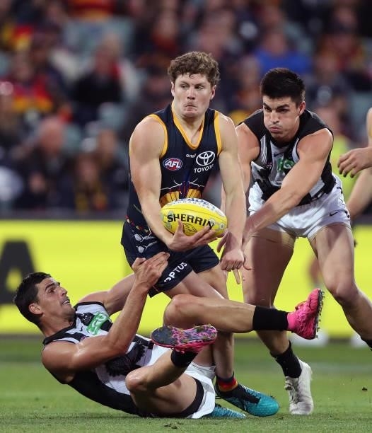 Lachlan Sholl of the Crows under pressure from Scott Pendlebury of the Magpies and Brayden Maynard of the Magpies during the 2021 AFL Round 12 match...