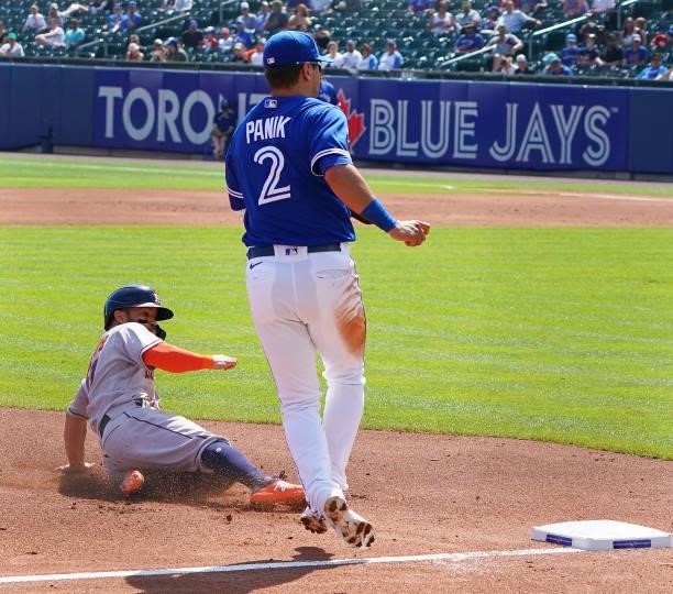 Jose Altuve of the Houston Astros steals third base as Joe Panik of the Toronto Blue Jays looks for the throw during the third inning at Sahlen Field...