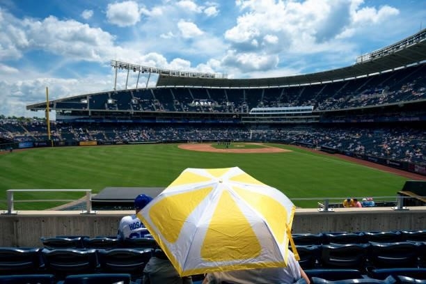 Kansas City Royals fans find shelter from the sun under an umbrella before the game against the Minnesota Twins at Kauffman Stadium on June 5, 2021...
