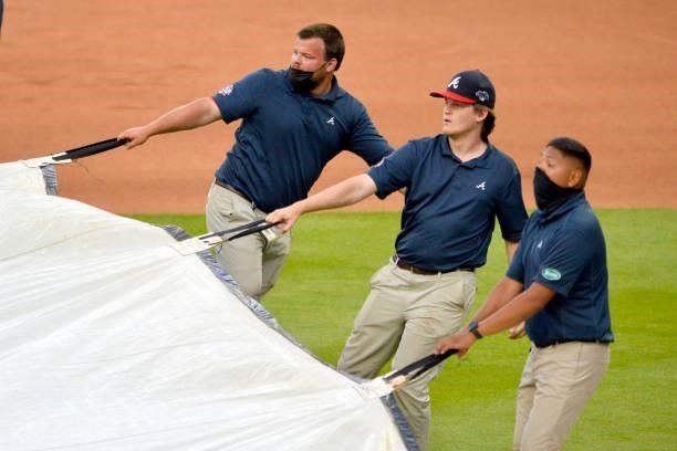Grounds crew workers roll out the tarp before the Atlanta Braves and Los Angeles Dodgers game at Truist Park on June 5, 2021 in Atlanta, Georgia.
