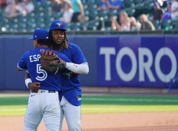 Santiago Espinal of the Toronto Blue Jays and Vladimir Guerrero Jr. #27 hug after beating the Houston Astros at Sahlen Field on June 5, 2021 in...