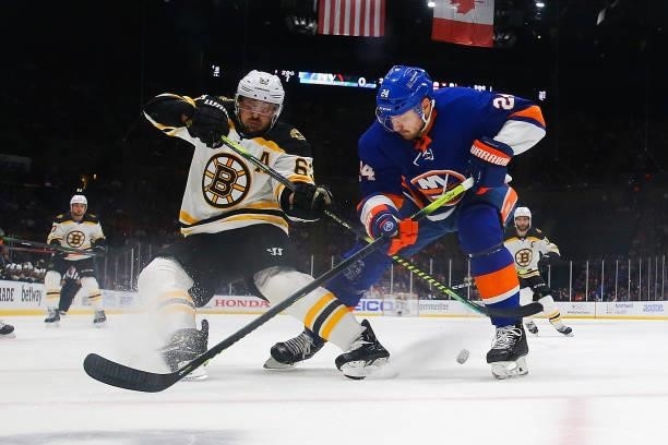 Brad Marchand of the Boston Bruins reaches for the puck against Scott Mayfield of the New York Islanders during the first period in Game Four of the...