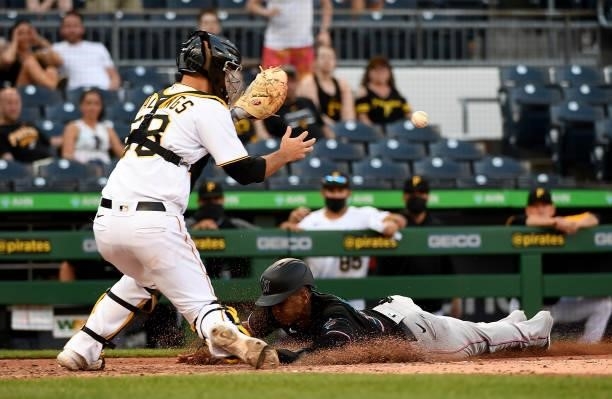 Magneuris Sierra of the Miami Marlins slides safely past Jacob Stallings of the Pittsburgh Pirates to score a run in the ninth inning during the game...