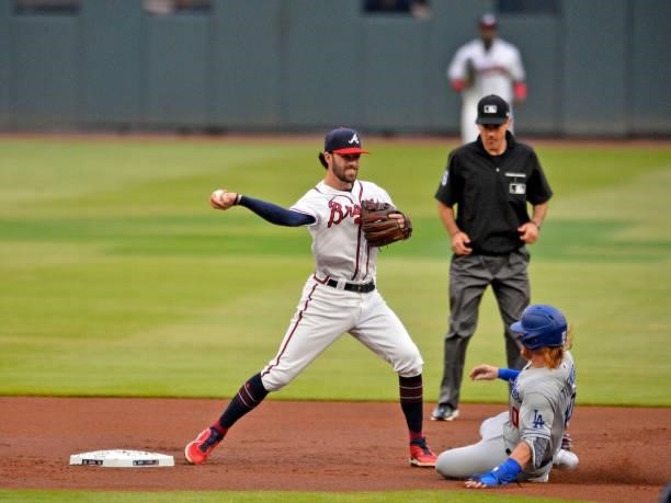 Dansby Swanson of the Atlanta Braves throws to first base as Justin Turner of the Los Angeles Dodgers slides into second base in the first inning at...