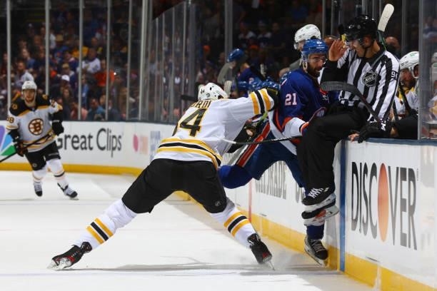 Linesman Bryan Pancich avoids a hit by Kyle Palmieri of the New York Islanders and Jarred Tinordi of the Boston Bruins during the first period in...