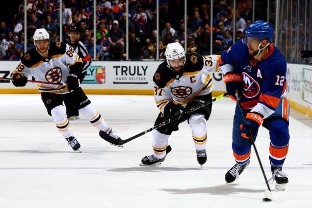 Josh Bailey of the New York Islanders handles the puck against Patrice Bergeron and David Pastrnak of the Boston Bruins during the third period in...