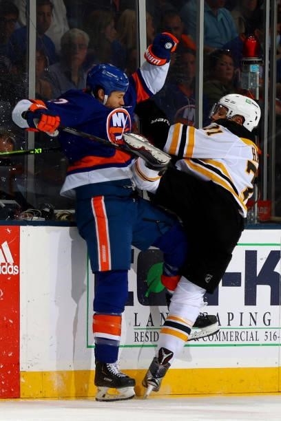 Taylor Hall of the Boston Bruins checks Matt Martin of the New York Islanders into the boards during the second period in Game Four of the Second...