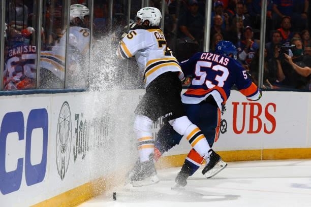 Charlie McAvoy of the Boston Bruins hits the boards against Casey Cizikas of the New York Islanders during the third period in Game Four of the...