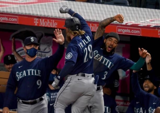 Jake Fraley of the Seattle Mariners is congratulated by manager Scott Servais and J.P. Crawford after hitting a grand slam home run in the fourth...