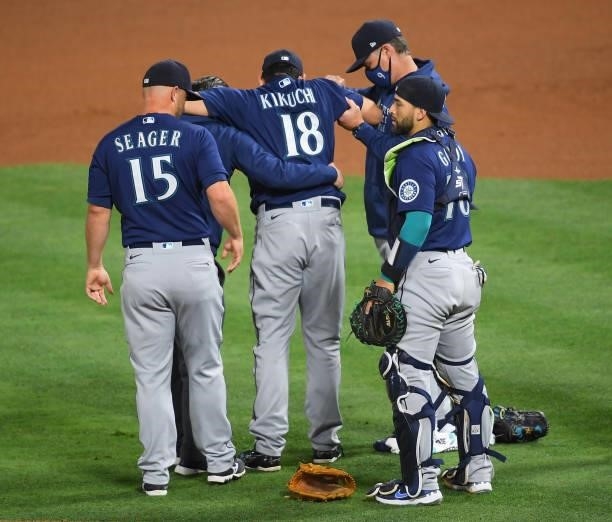Yusei Kikuchi of the Seattle Mariners is helped off the field by manager Scott Servais after he was hit by a line drive hit by David Fletcher of the...