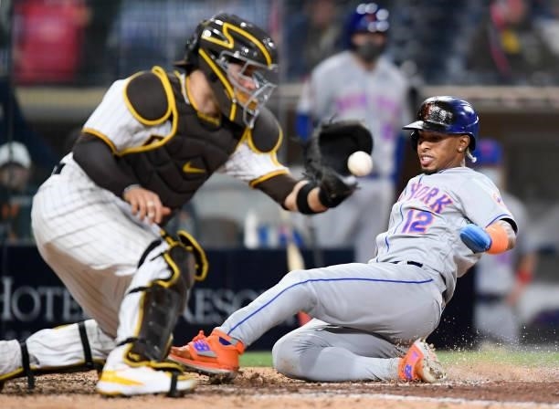 Francisco Lindor of the New York Mets scores ahead of the throw to Victor Caratini of the San Diego Padres during the ninth inning of a baseball game...