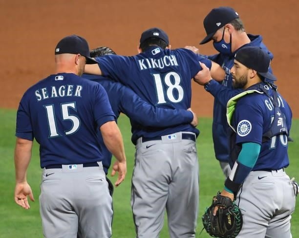 Yusei Kikuchi of the Seattle Mariners is helped off the field by manager Scott Servais after he was hit by a line drive hit by David Fletcher of the...