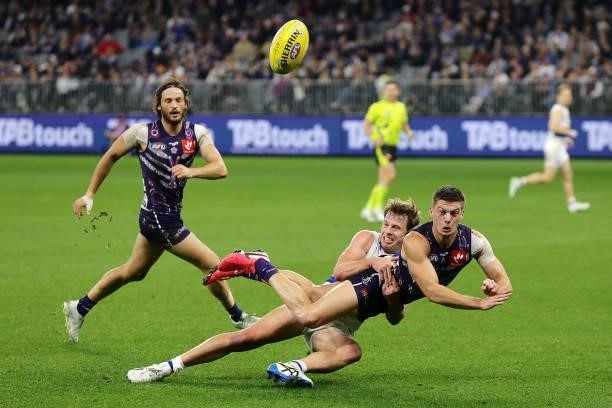 Darcy Tucker of the Dockers is tackled by Mitch Hannan of the Bulldogs during the 2021 AFL Round 12 match between the Fremantle Dockers and the...