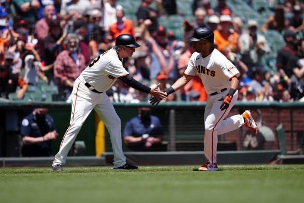 Third base coach Ron Wotus of the San Francisco Giants high fives LaMonte Wade Jr after Wade hit a home run during the game between the Chicago Cubs...