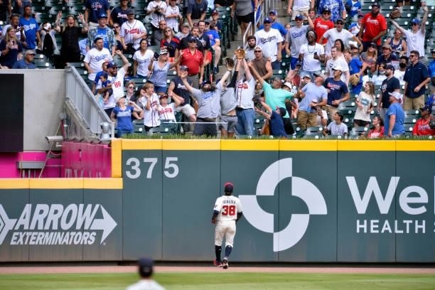 Guillermo Heredia, of the Atlanta Braves watches as fans clamor for a home run ball hit by Albert Pujols of the Los Angeles Dodgers in the 9th inning...