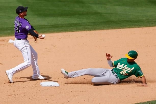 Ryan McMahon of the Colorado Rockies throws to first base after forcing out Matt Olson of the Oakland Athletics at second base but was unable to...