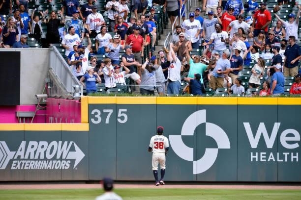 Guillermo Heredia, of the Atlanta Braves watches as fans clamor for a home run ball hit by Albert Pujols of the Los Angeles Dodgers in the 9th inning...