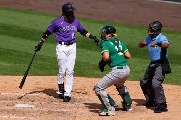 Charlie Blackmon of the Colorado Rockies reacts after being called out on strikes by home plate umpire Ramon DeJesus as catcher Sean Murphy of the...