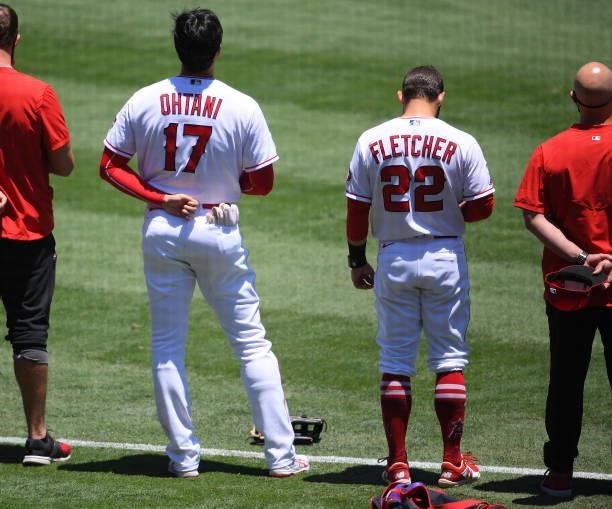 Shohei Ohtani stands next to David Fletcher of the Los Angeles Angels during the National Anthem before the game against the Seattle Mariners at...