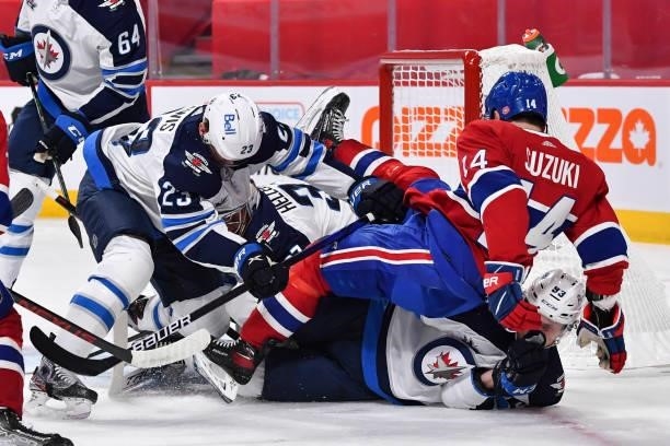 Trevor Lewis of the Winnipeg Jets pushes Nick Suzuki of the Montreal Canadiens over Kristian Vesalainen during the second period in Game Three of the...