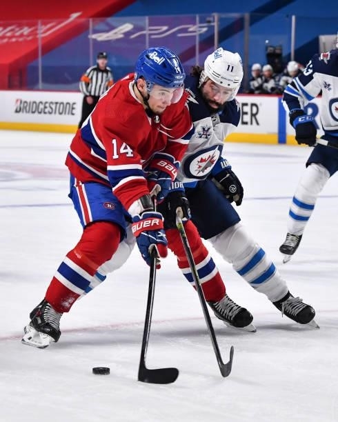 Nick Suzuki of the Montreal Canadiens skates the puck against Nate Thompson of the Winnipeg Jets during the second period in Game Three of the Second...