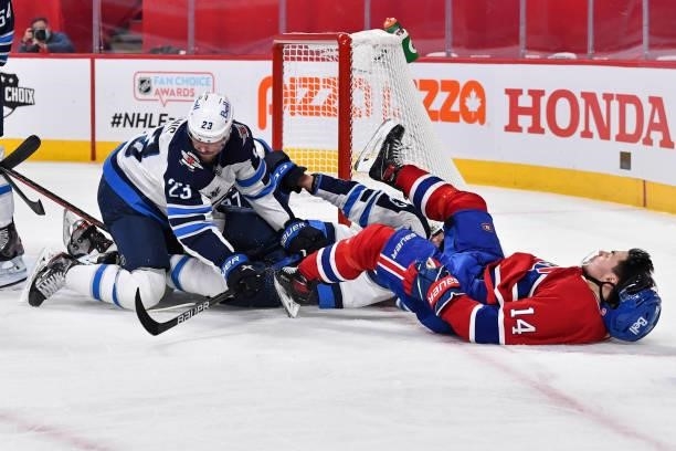 Trevor Lewis of the Winnipeg Jets pushes Nick Suzuki of the Montreal Canadiens over Kristian Vesalainen during the second period in Game Three of the...