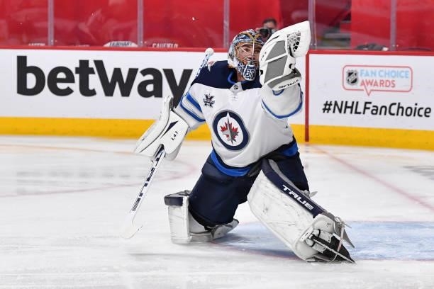 Goaltender Connor Hellebuyck of the Winnipeg Jets makes a glove save against the Montreal Canadiens during the second period in Game Three of the...
