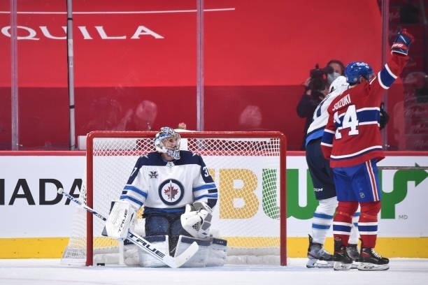 Goaltender Connor Hellebuyck of the Winnipeg Jets looks at Nick Suzuki of the Montreal Canadiens as he celebrates his goal during the third period in...