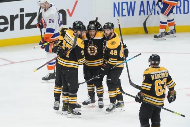 David Pastrnak of the Boston Bruins hugs his line mates after scoring in the third period against the New York Islanders in Game Five of the Second...