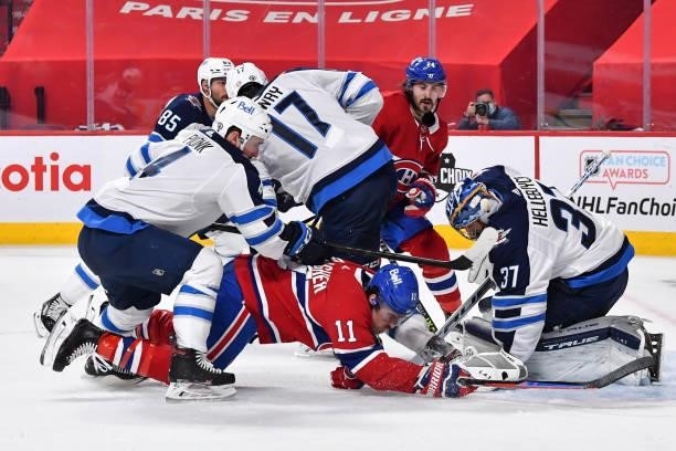 Neal Pionk of the Winnipeg Jets takes down Brendan Gallagher of the Montreal Canadiens near goaltender Connor Hellebuyck during the second period in...