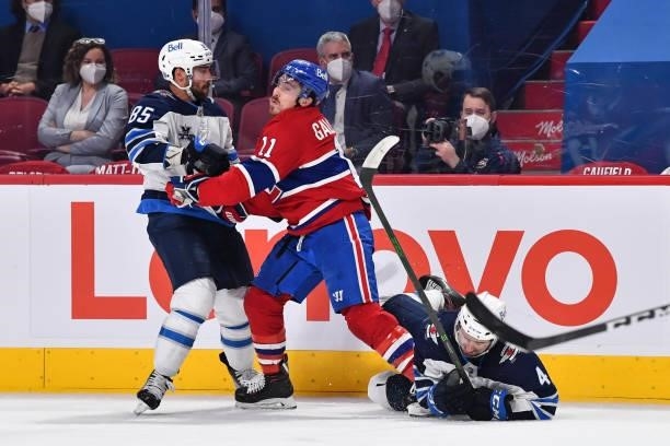 Brendan Gallagher of the Montreal Canadiens and Mathieu Perreault of the Winnipeg Jets battle along the boards while Neal Pionk of the Winnipeg Jets...