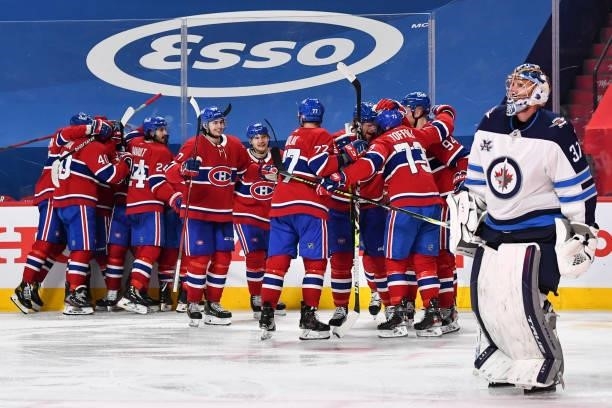 The Montreal Canadiens celebrate an overtime victory as goaltender Connor Hellebuyck of the Winnipeg Jets skates by in Game Four of the Second Round...