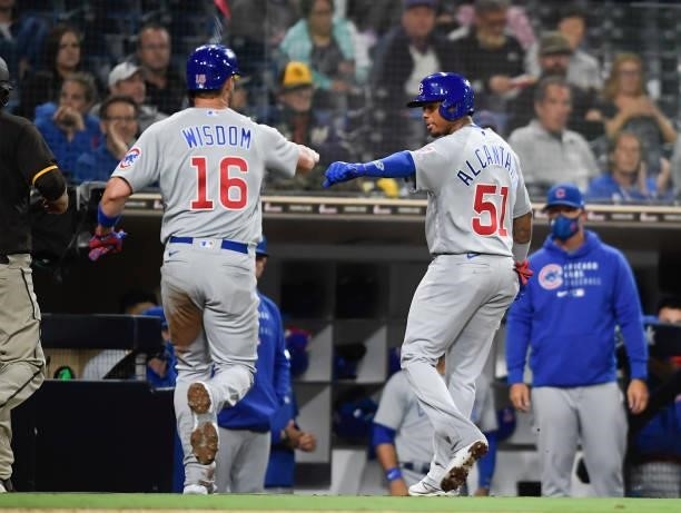 Patrick Wisdom of the Chicago Cubs and Sergio Alcantara fist bump after scoring during the fourth inning of a baseball game against the San Diego...