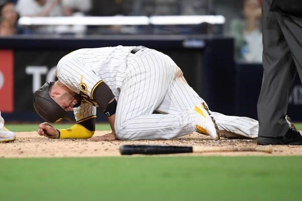 Victor Caratini of the San Diego Padres lies on the ground after scoring during the sixth inning of a baseball game against the Chicago Cubs at Petco...