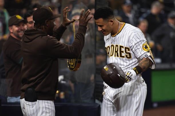 Jorge Mateo places the 'swag chain' on Manny Machado of the San Diego Padres after Machado's home run in the eighth inning against the Chicago Cubs...