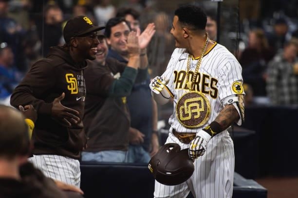 Jorge Mateo places the 'swag chain' on Manny Machado of the San Diego Padres after Machado's home run in the eighth inning against the Chicago Cubs...