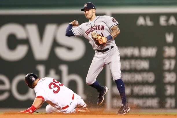 Carlos Correa of the Houston Astros turns a double play over the slide of Xander Bogaerts of the Boston Red Sox in the eighth inning of a game at...