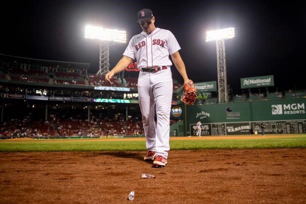 Hunter Renfroe of the Boston Red Sox removes bottles thrown onto the field by fans during the ninth inning of a game against the Houston Astros on...
