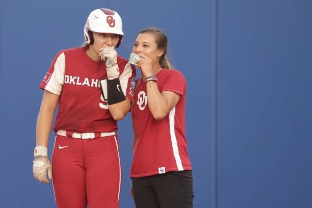 Kinzie Hansen of the Oklahoma Sooners talks with first base coach Sydney Romero during the Division I Women's Softball Championship held at ASA Hall...