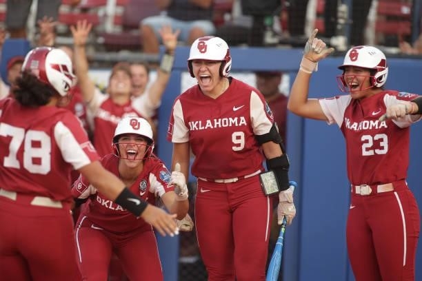 Jocelyn Alo of the Oklahoma Sooners is greeted at home plate by her teammates Kinzie Hansen and Tiare Jennings after hitting a home run during the...
