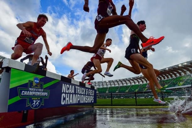 Runners in the 3,000 meter steeplechase clear the water jump during the Division I Men's and Women's Outdoor Track & Field Championships held at...