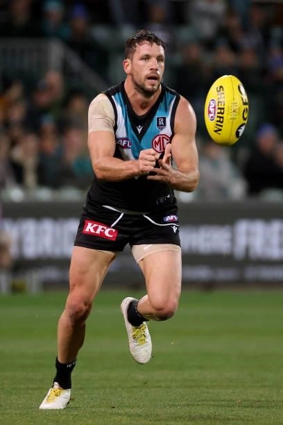 Travis Boak of the Power handpasses the ball during the 2021 AFL Round 13 match between the Port Adelaide Power and the Geelong Cats at Adelaide Oval...
