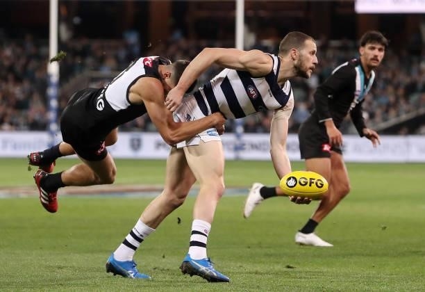 Sam Menegola of the Cats handpasses the ball while Ryan Burton of the Power tackles during the 2021 AFL Round 13 match between the Port Adelaide...
