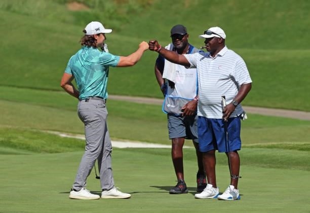 Charlie Saxon and Sterling Sharpe fist bump after making a birdie on the fourth hole during the first round of the BMW Charity Pro-Am presented by...