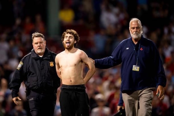Fan is escorted after running onto the field during the sixth inning of a game between the Boston Red Sox and the Houston Astros on June 10, 2021 at...